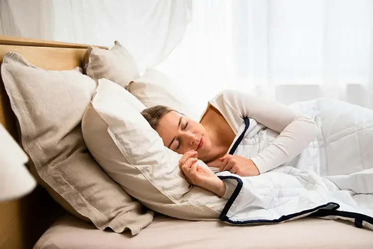 A woman lying on her side, sleeping in bed.