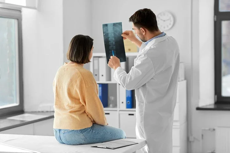 A doctor showing an X-ray to a female patient during a medical consultation to identify underlying causes of pain.