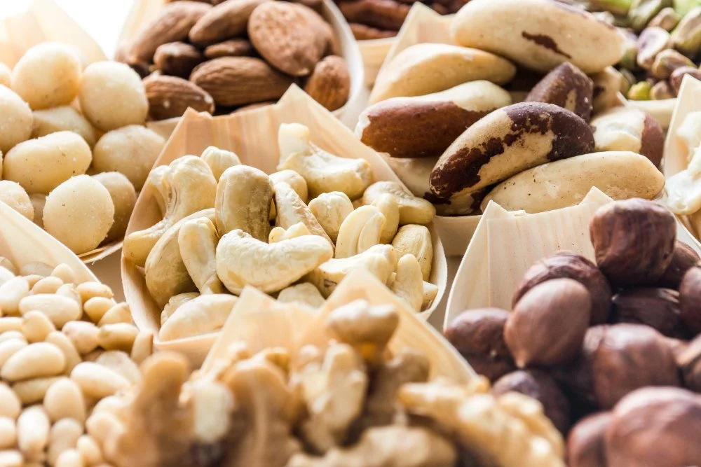Close-up of assorted nuts including almonds, macadamia nuts, Brazil nuts, pistachios, cashews, pine nuts, and walnuts — a nutritious blend packed with healthy fats, protein, and antioxidants.