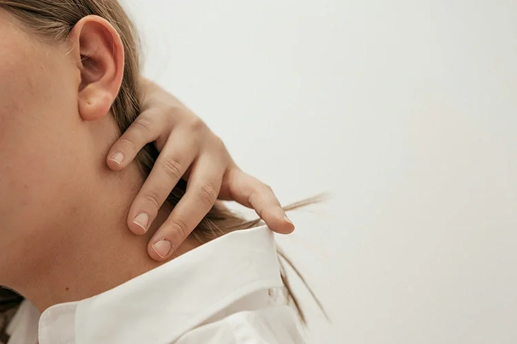 A woman cautiously touching her neck after a minor car accident, showing uncertainty about her pain and emphasizing the importance of monitoring delayed symptoms.