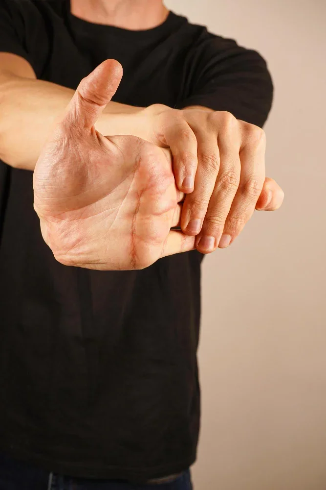 A man extends one arm and gently pulls back his fingers to relieve wrist and forearm tension.