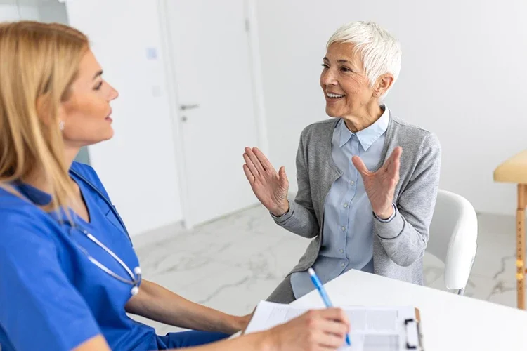 Smiling patient describing her symptoms to a doctor during a friendly consultation in a medical office.