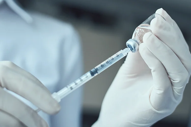 A doctor is drawing medication from a vial into a syringe.