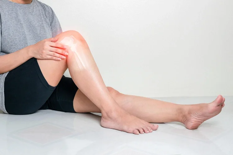 A realistic photo of a person’s leg illustrating knee joint inflammation and discomfort due to osteoarthritis, with the affected area emphasized in red against a white background.