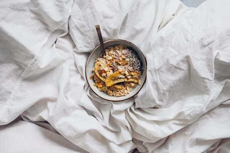 A healthy granola bowl on a bed, representing nutrition for stress recovery and wellness.
