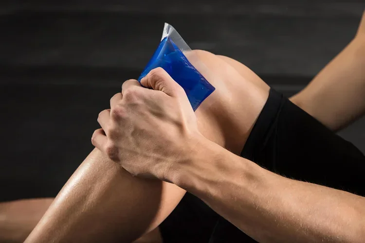 Person applying an ice bag to their knee for pain relief and swelling reduction.