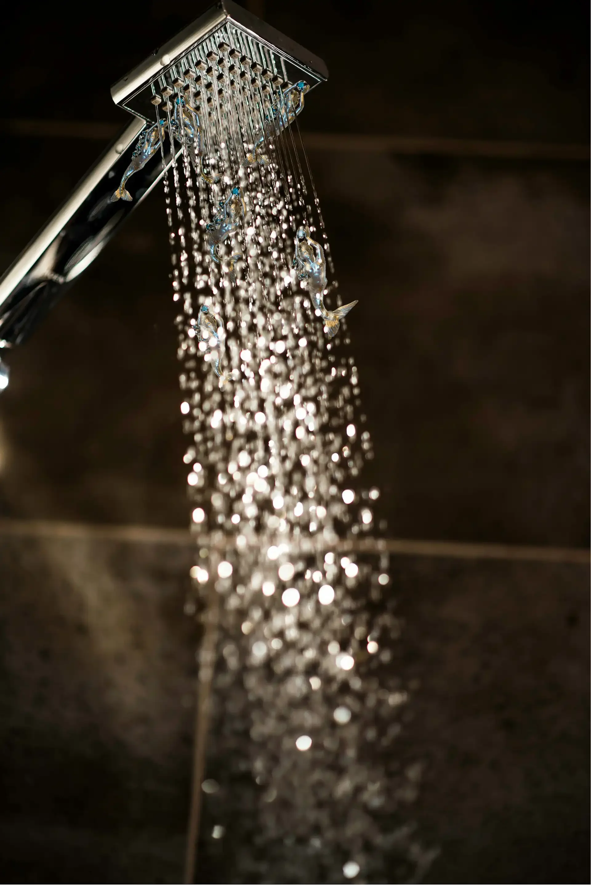 Close-up of cold water droplets falling from a modern showerhead used for cold thermogenesis and vagus nerve activation.