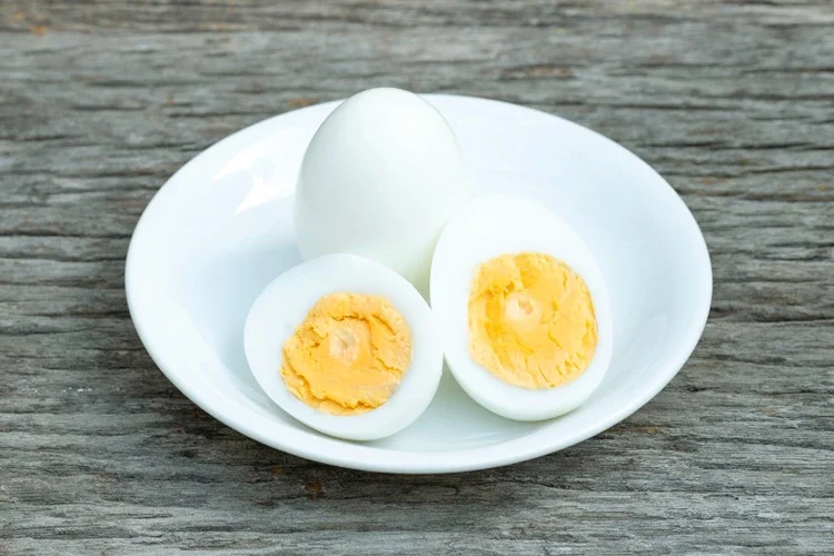 Perfectly hard-boiled eggs, peeled and halved, presented on a white plate. It emphasizes a convenient, high-protein snack that supports muscle recovery and keeps you feeling full throughout the day.