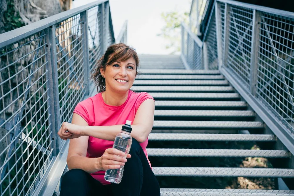 Portrait of a smiling woman standing outdoors on a sunny day, radiating confidence and natural beauty.