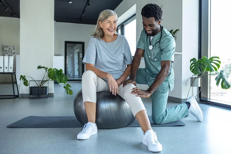 A professional rehabilitation specialist manipulating a patient’s knee to check the range of motion after treatment, highlighting a return to daily activities.