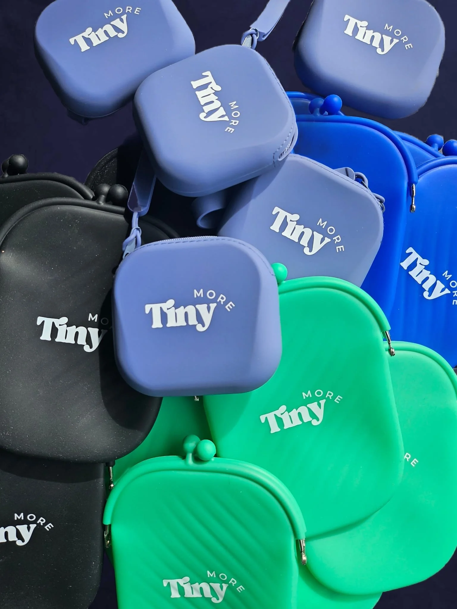 Colorful travel pouches in various colors, including black, blue, green, and black, all with white text that reads 'Tiny More'. Reusable and splash-proof silicone containers showing quality of pouch to hold condiments.