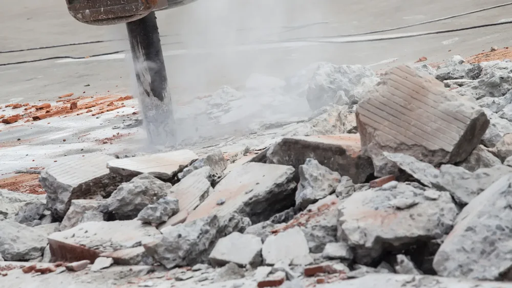 Hydraulic breaker creating dust while removing concrete and brick