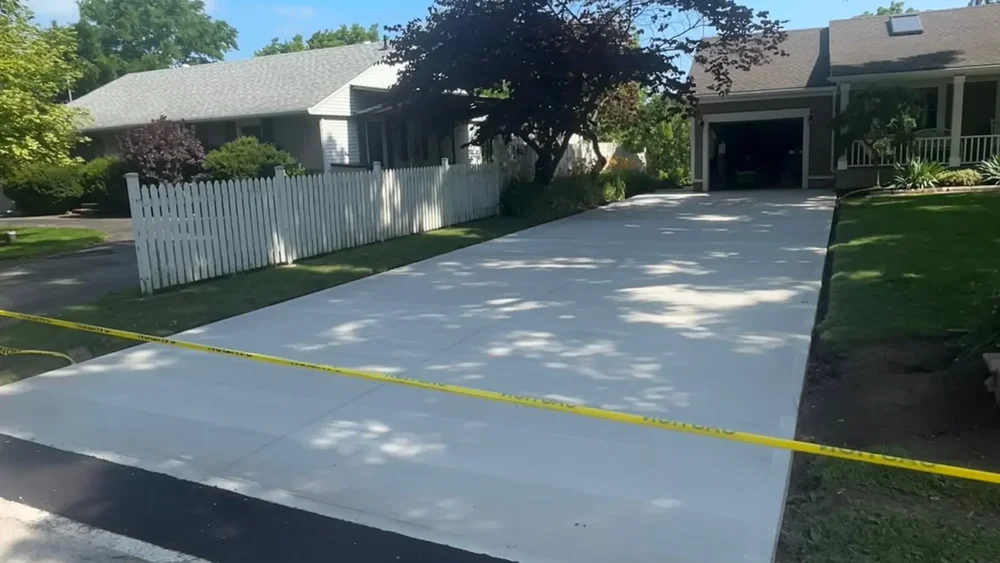 Newly installed broom-finish concrete driveway with caution tape in Lincoln