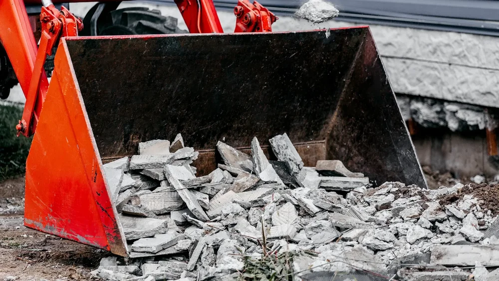 Loader bucket filled with broken concrete debris during excavation