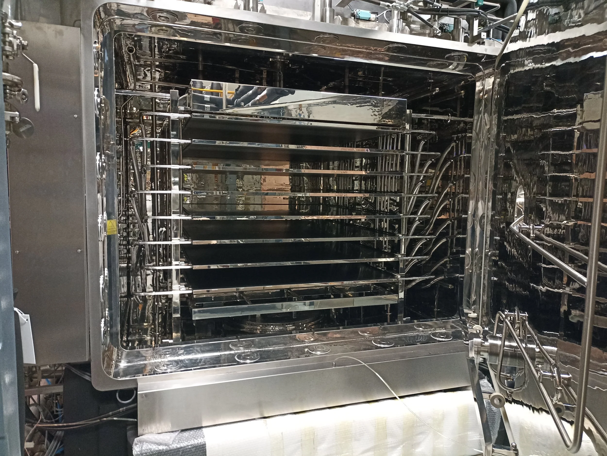 Horno de laboratorio de acero inoxidable con varias bandejas dentro.