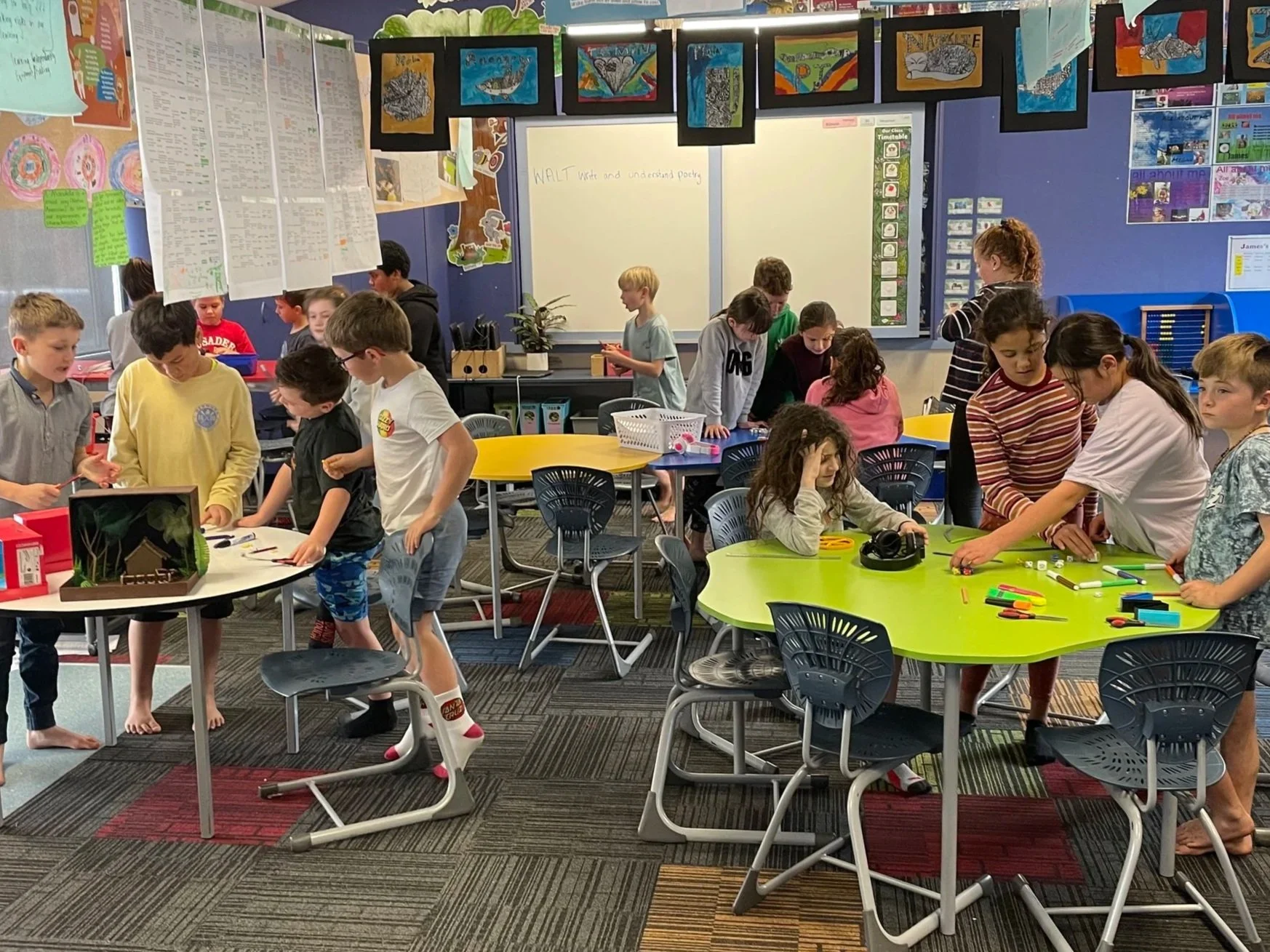 Classroom filled with children engaging in activities around tables with school supplies