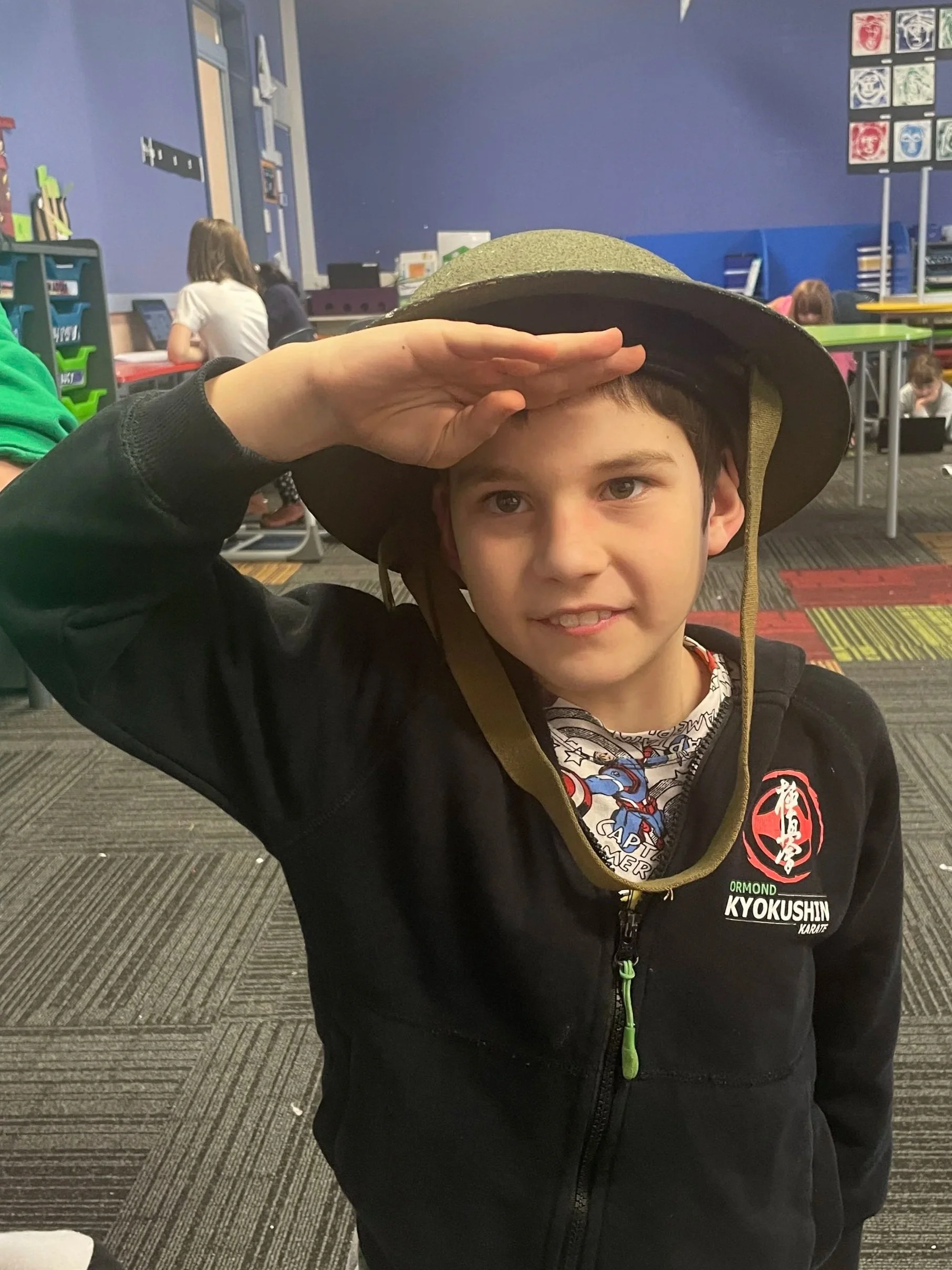 A young boy posing while wearing an army hat