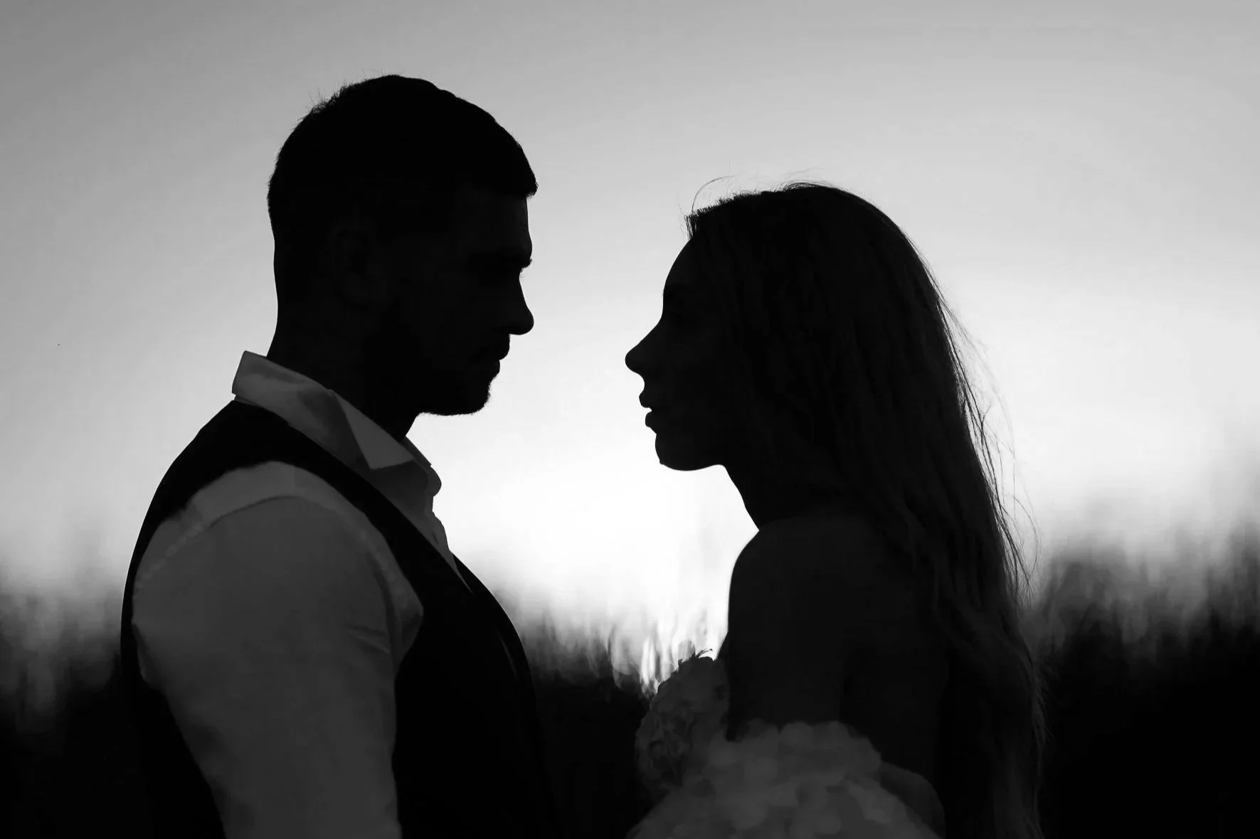 Silhouette of a man and woman facing each other at sunset, with blurred landscape in the background M&ZPhotostory | Bulgaria