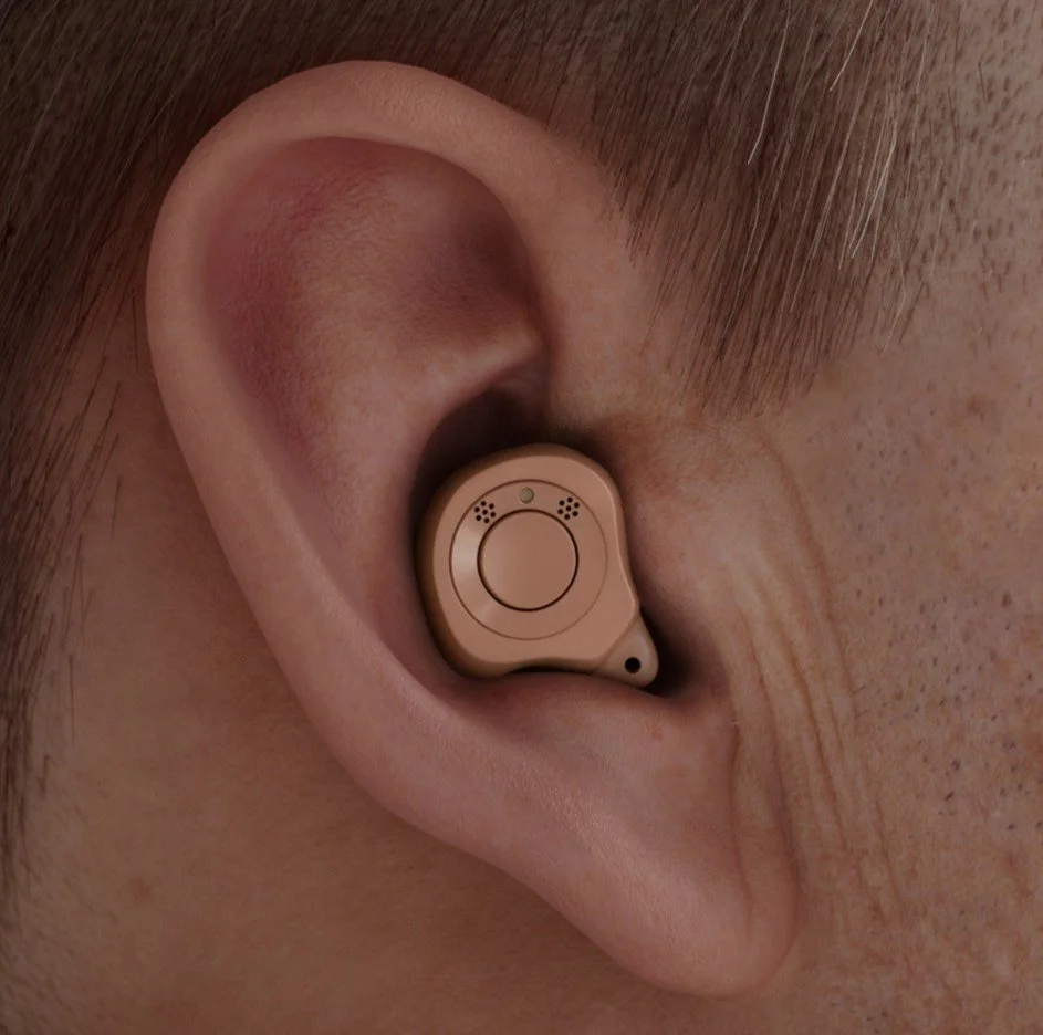 A close-up of a human ear with a beige hearing aid inserted.