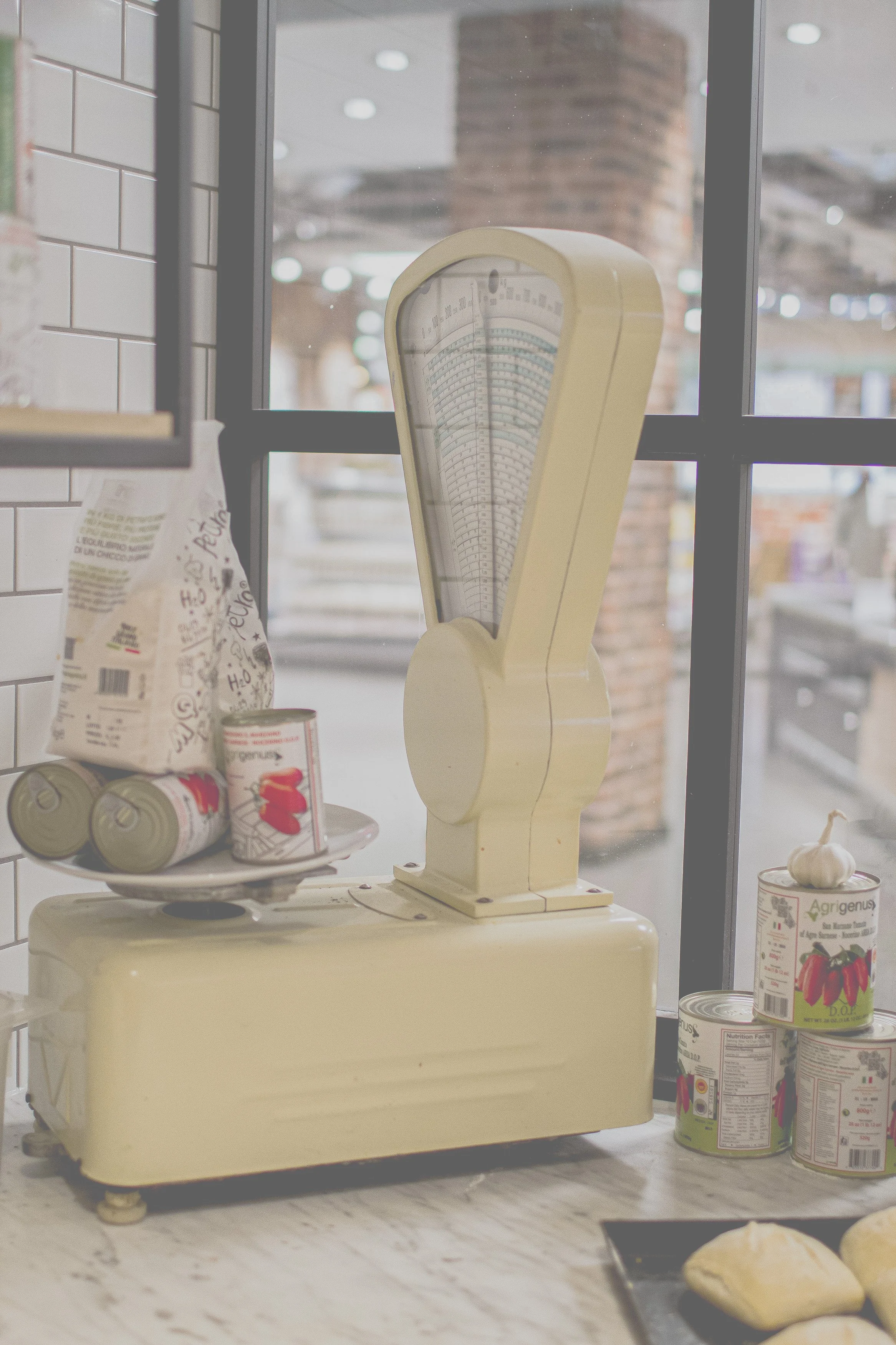 Alte Waage in einer Bäckerei, daneben eingeweckte Tomaten und eine Knoblauchknolle auf einer Theke.