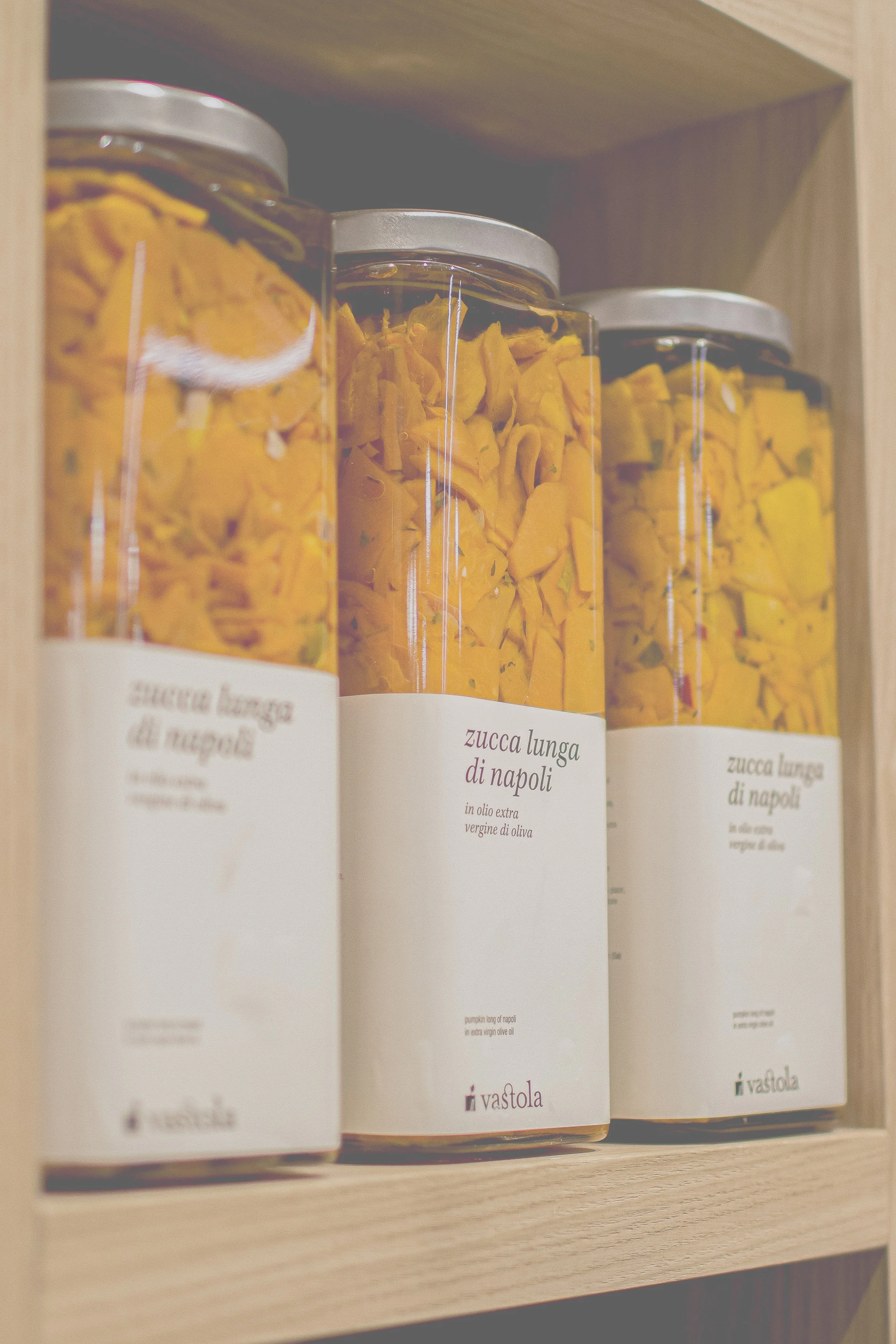 Glasbehälter mit in Öl eingelegtem, getrocknetem Kürbiskuchen auf einem Holzbord.