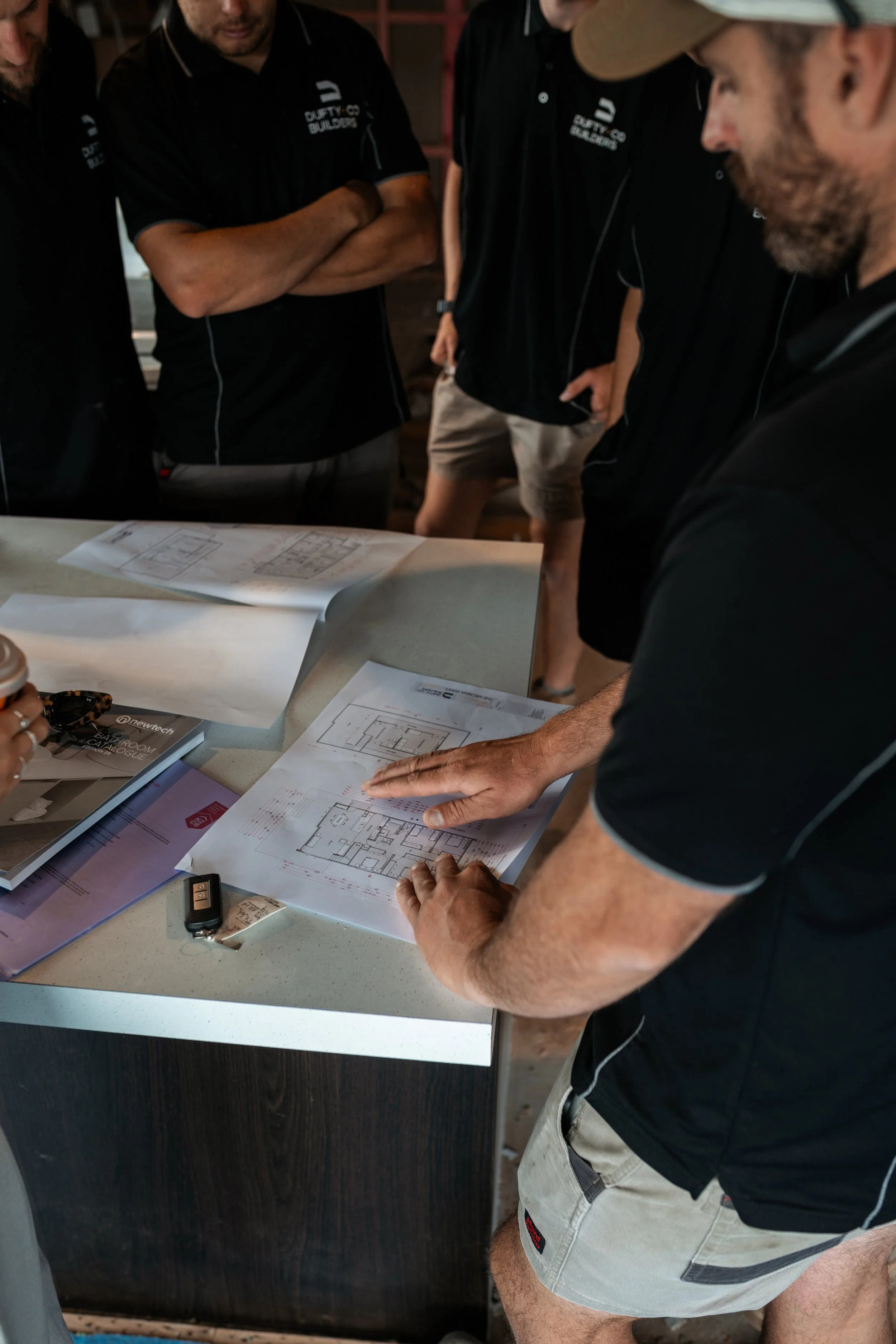 Group of construction workers discussing blueprints and architectural plans at a work site.