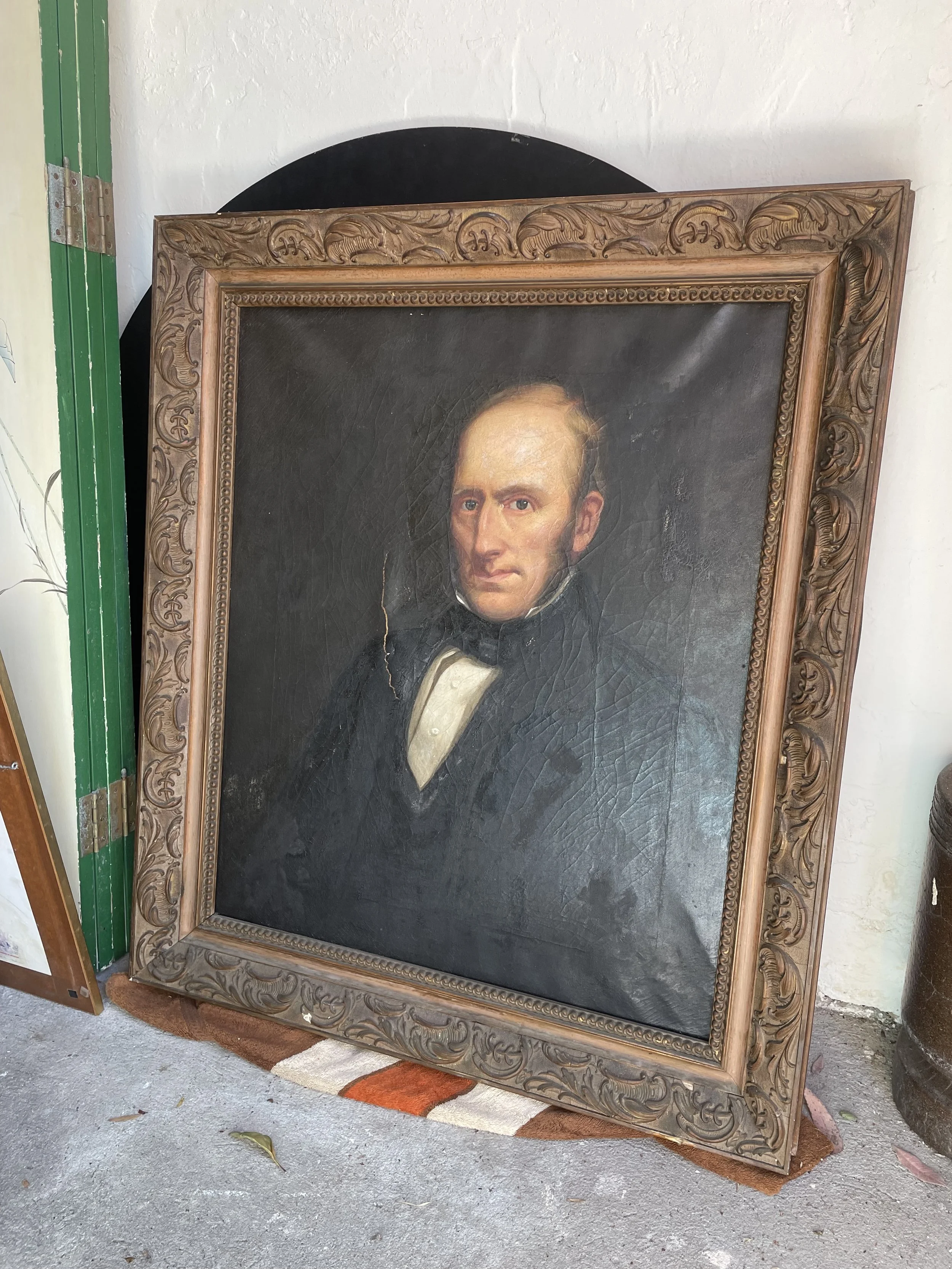 Antique framed portrait painting of a man in formal attire with dark background.