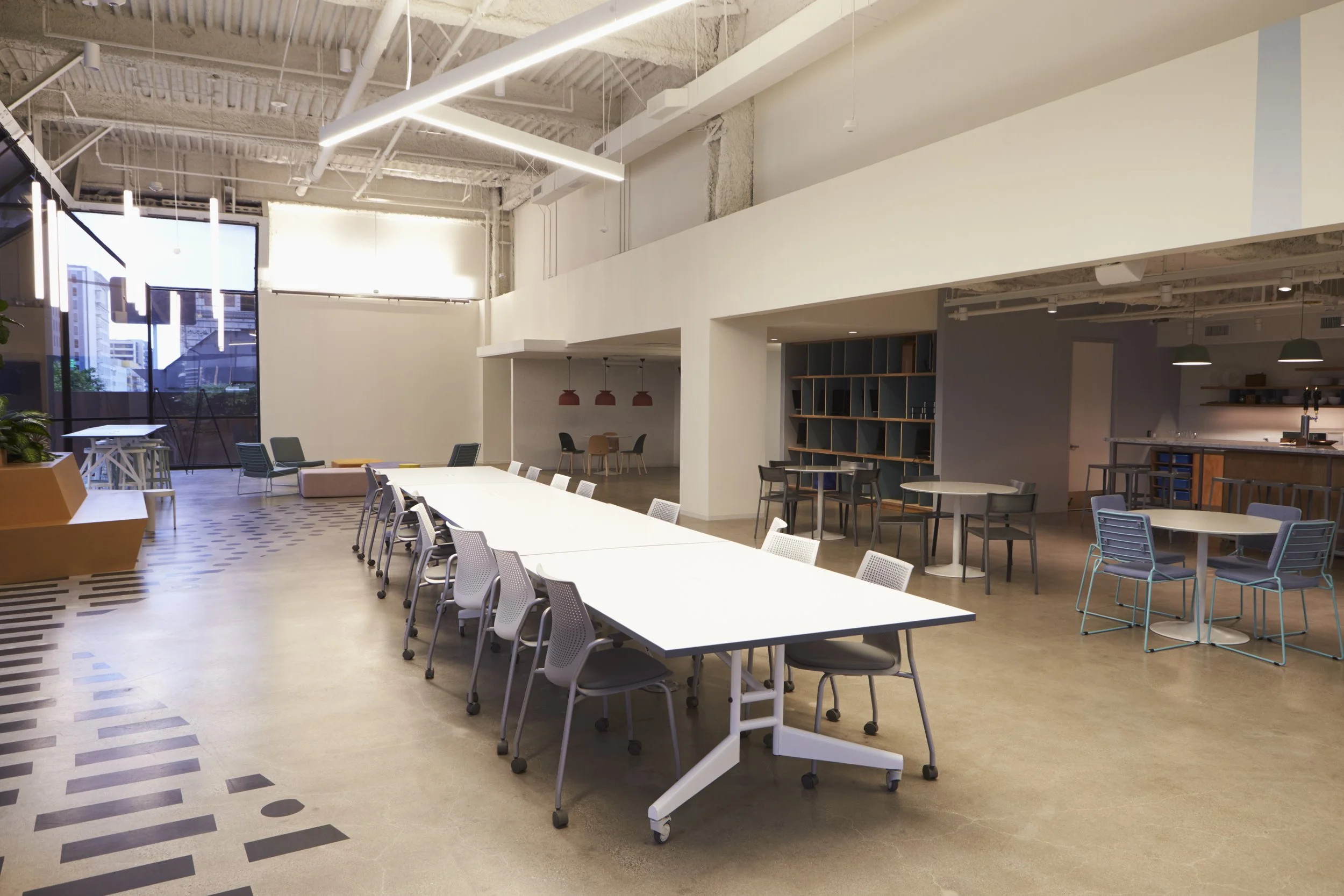 matterport photo scan of Modern office or coworking space with high ceilings, large windows, and various tables and chairs for meetings and work