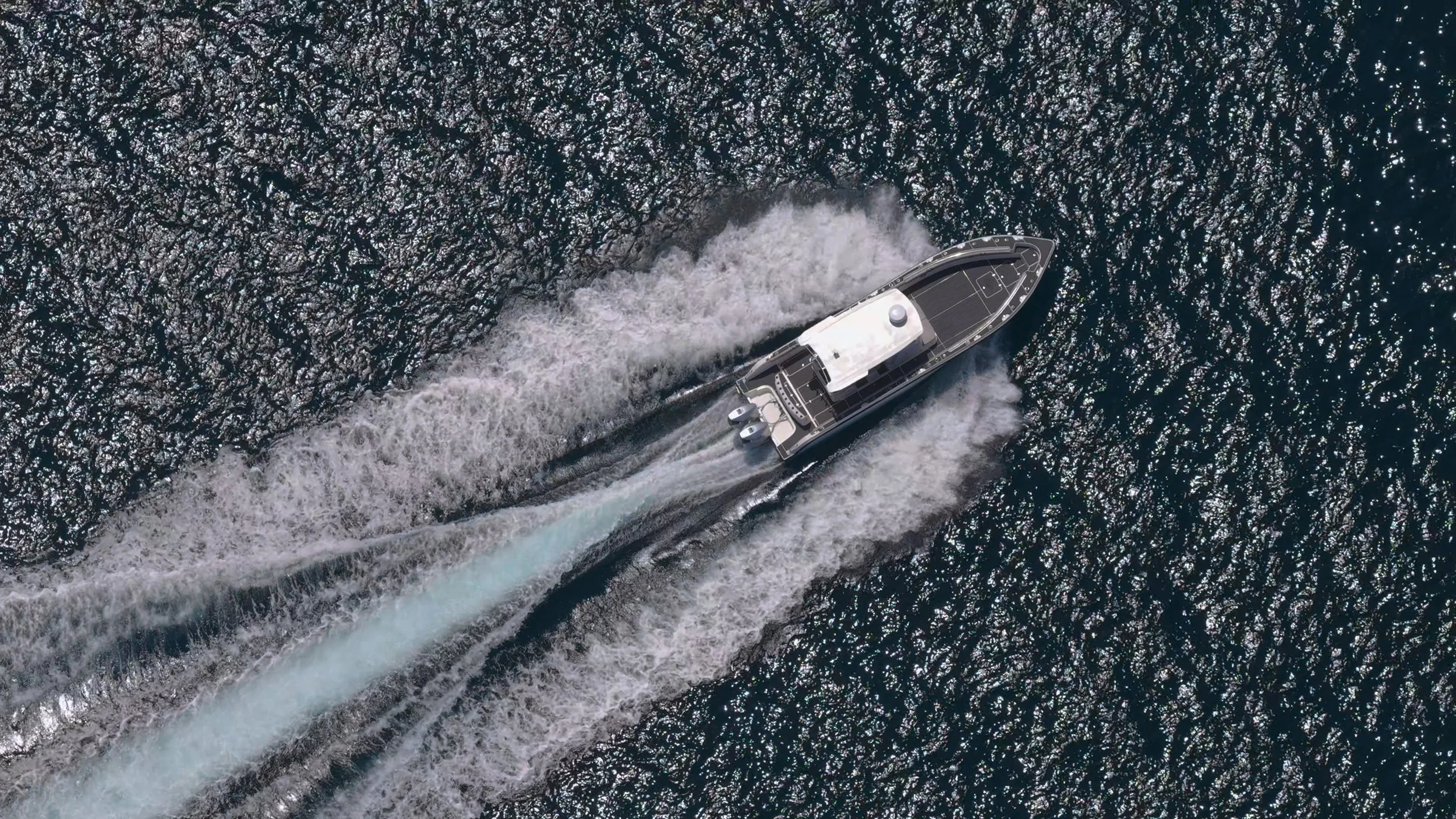 An aerial view of a boat moving through the water, creating a wake behind it.