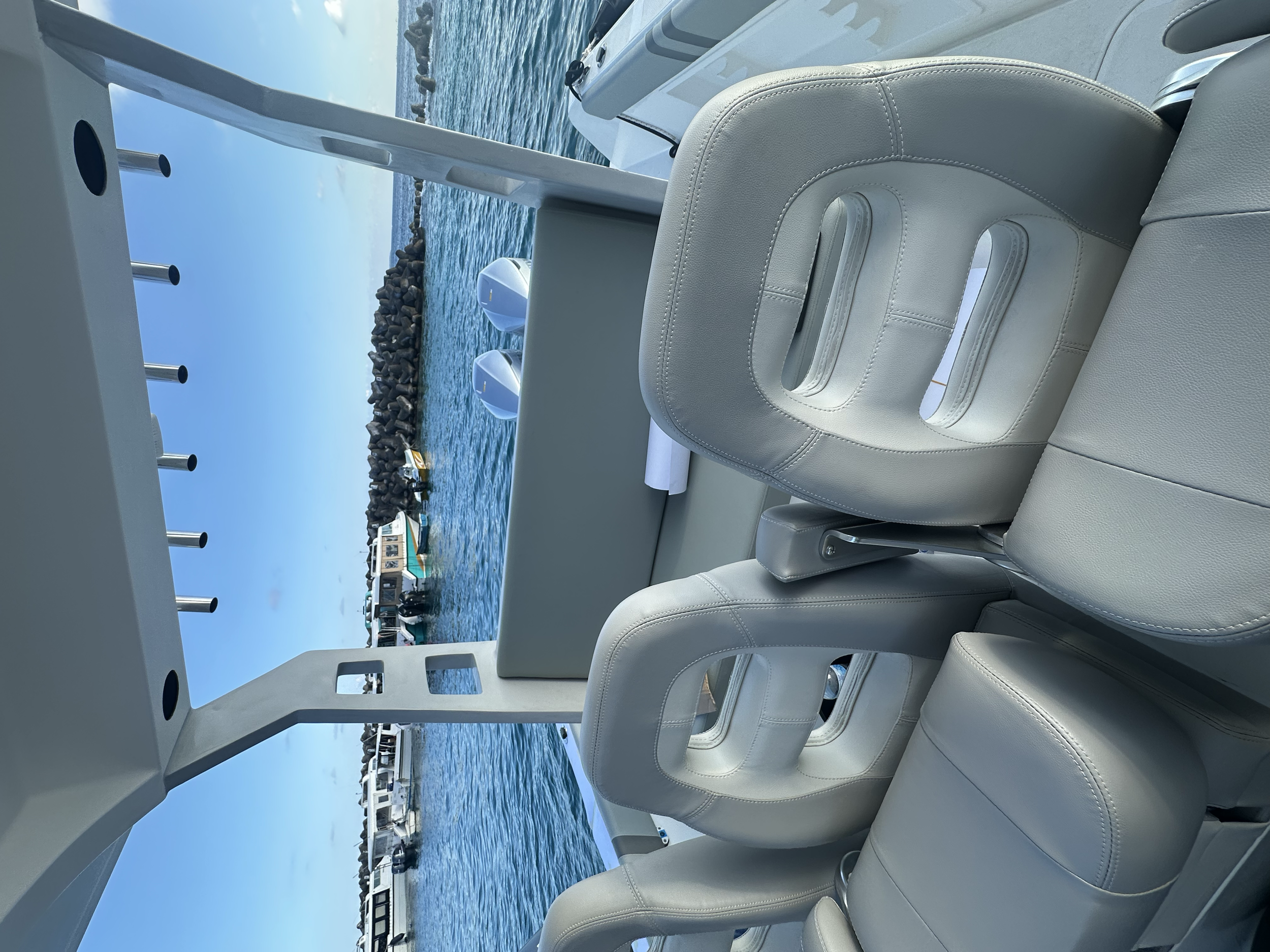 Interior view of a yacht with white leather seats and a window showing a view of boats and water outside.