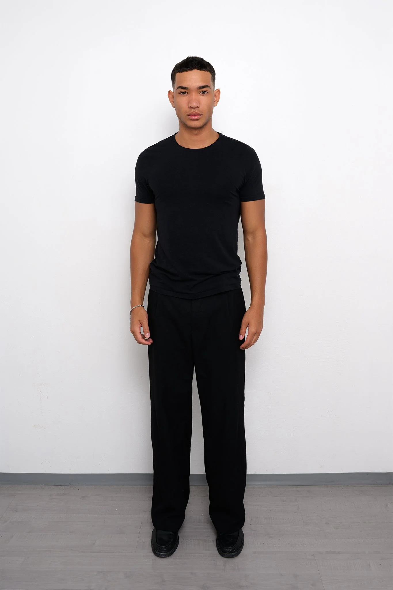 Ganzkörper Model Polaroid von Luis in schlichtem schwarzem Outfit, fotografiert im Peter Becher Studio Nürnberg.