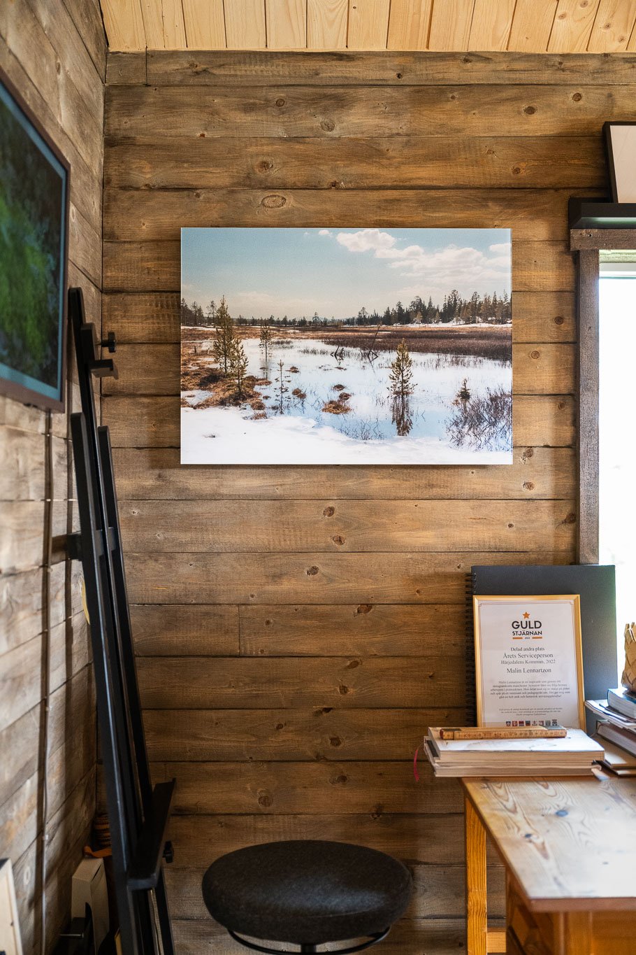 Fotokonst med naturmotiv av byMalott, upphängd på en trävägg i gårdsbutiken.