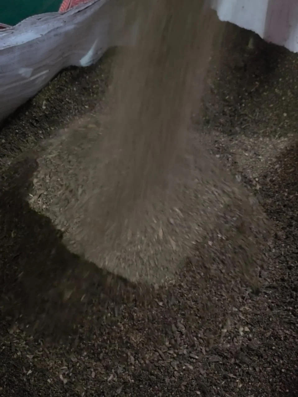 Soil being poured onto a garden bed from a scoop or container.