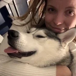 A woman hugs her husky dog 