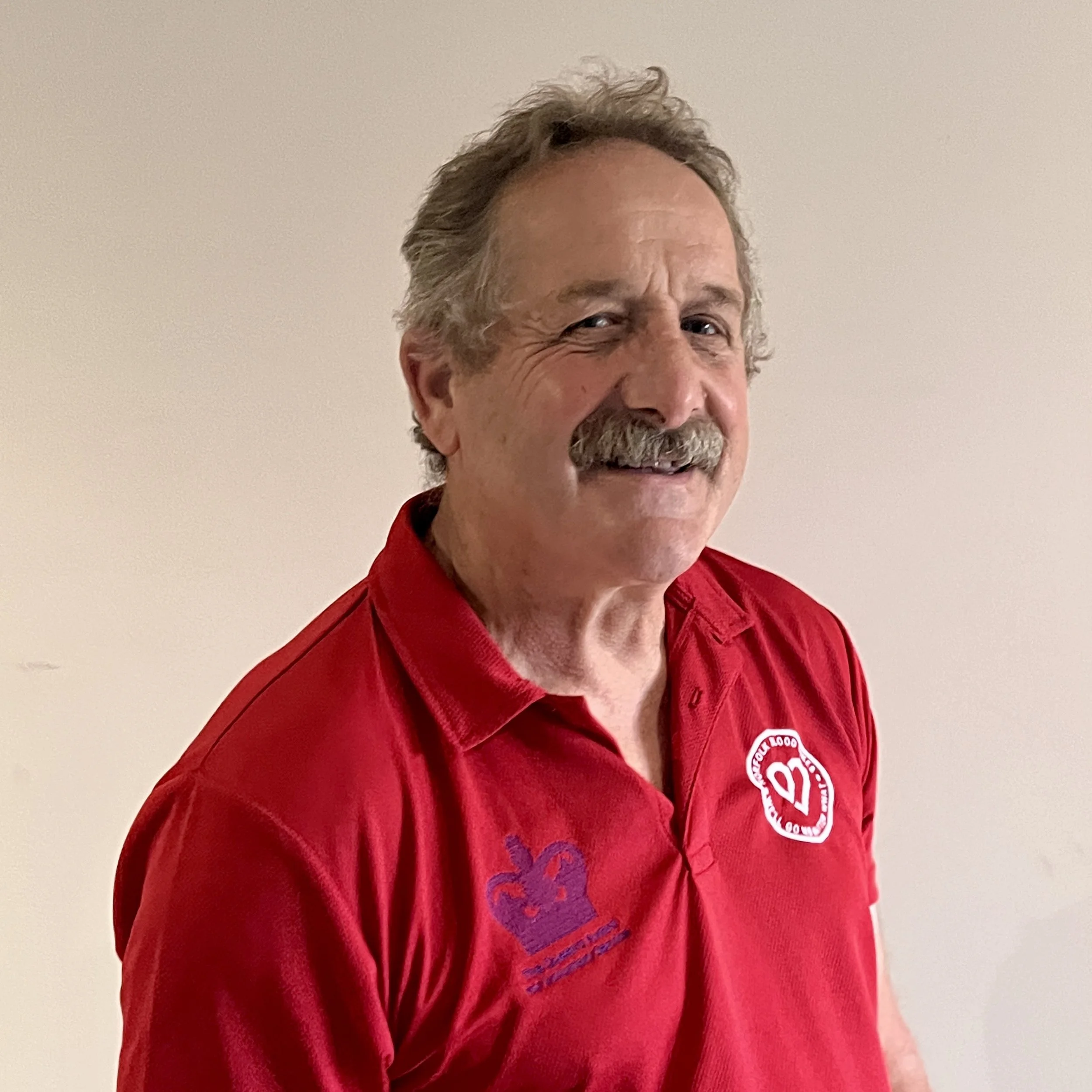 A man sitting on a BMW motorcycle outdoors with trees and a partly cloudy sky in the background.