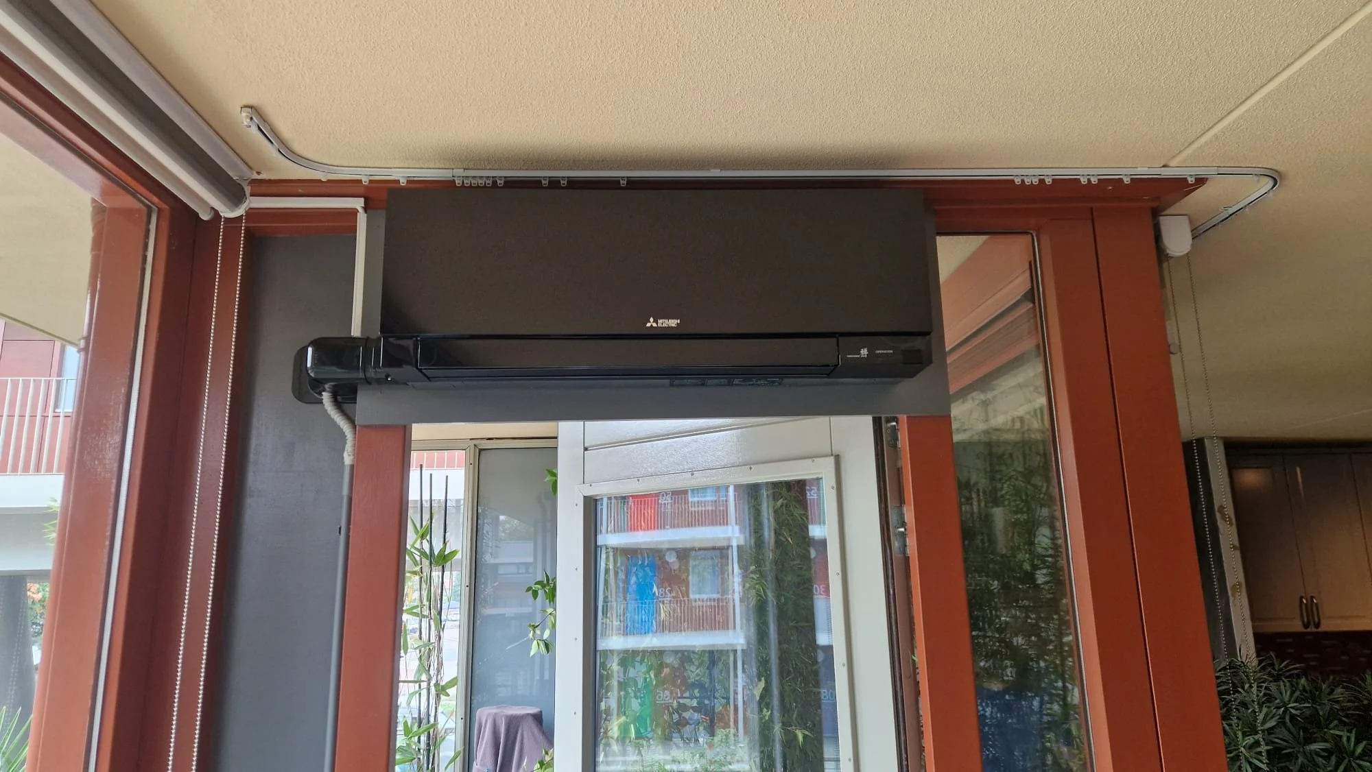 Muur met airconditioning en grote ramen in een woonkamer.