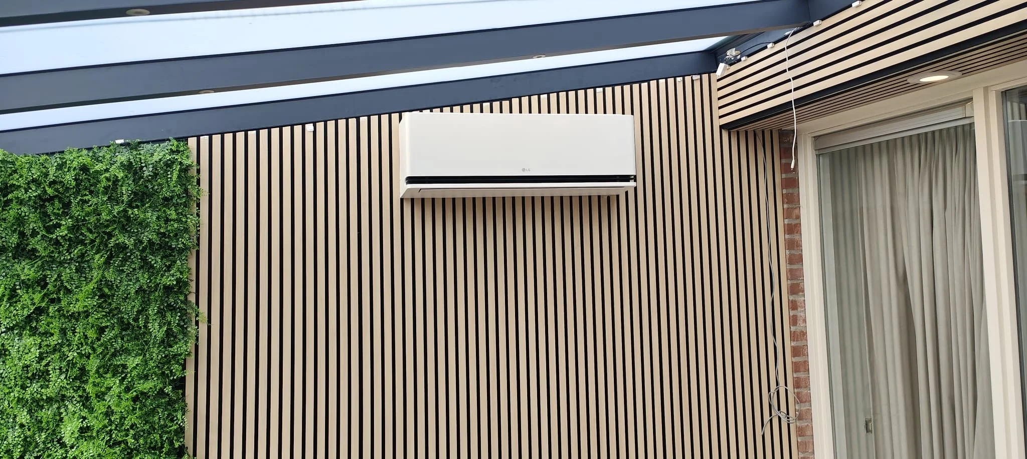 Buitenscherm met een groene muur en een airconditioner op een betegeld muur.