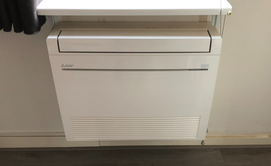 Een wit apparaat, mogelijk een airconditioner of vrieskast, onder een werkblad.