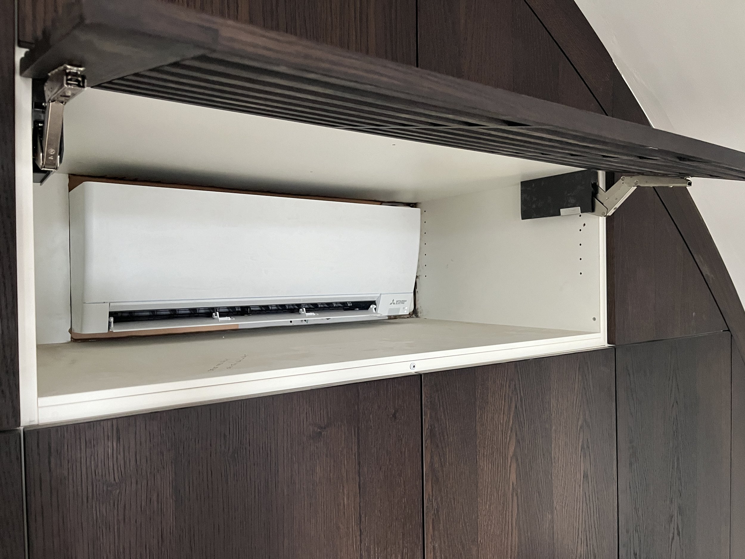 Binnenkant van een bedieningskast voor een airconditioning, zonder frontpaneel, met de binnenkant zichtbaar.