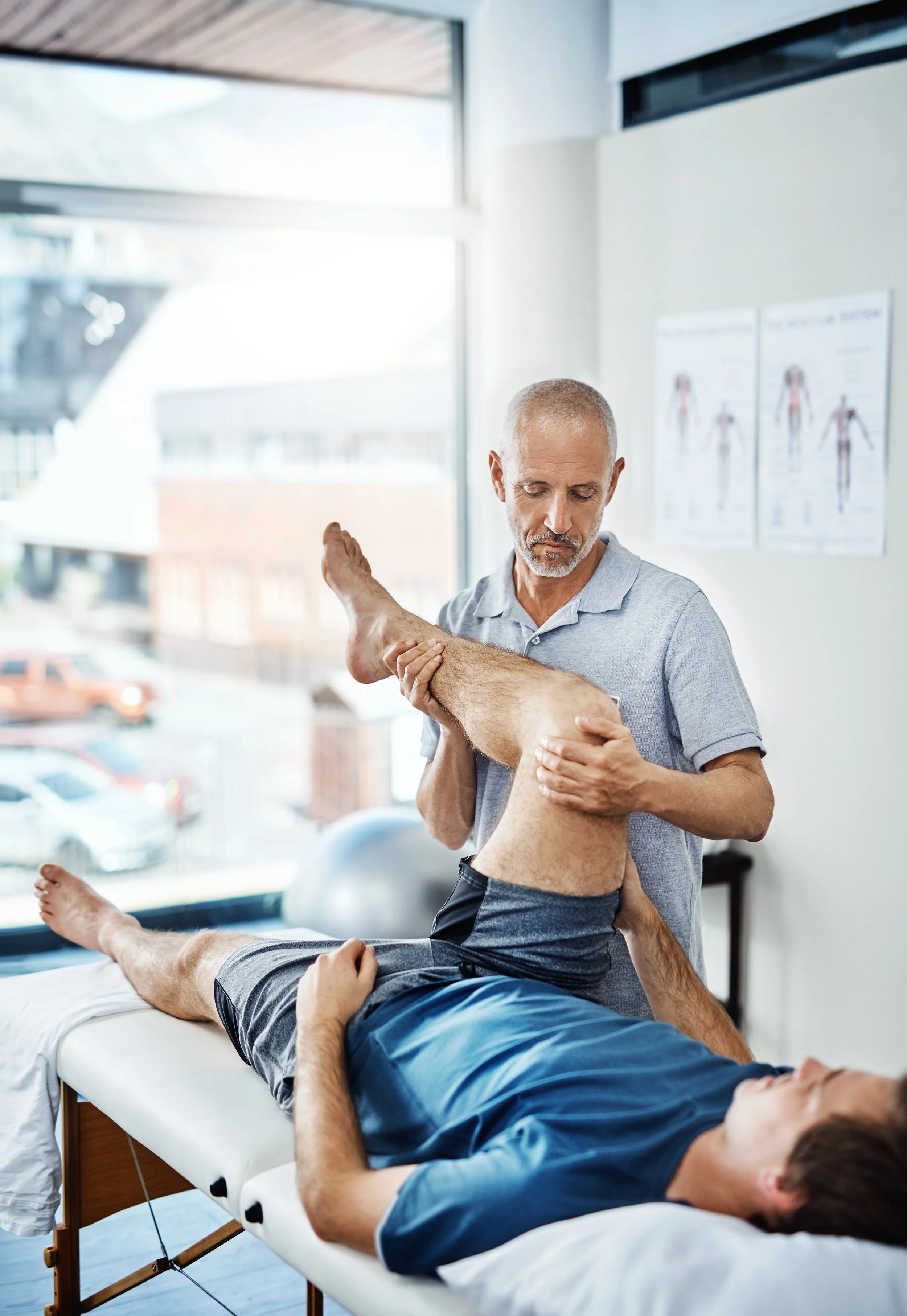 Médico a realizar exercícios de reabilitação de lesões musculares com o paciente.