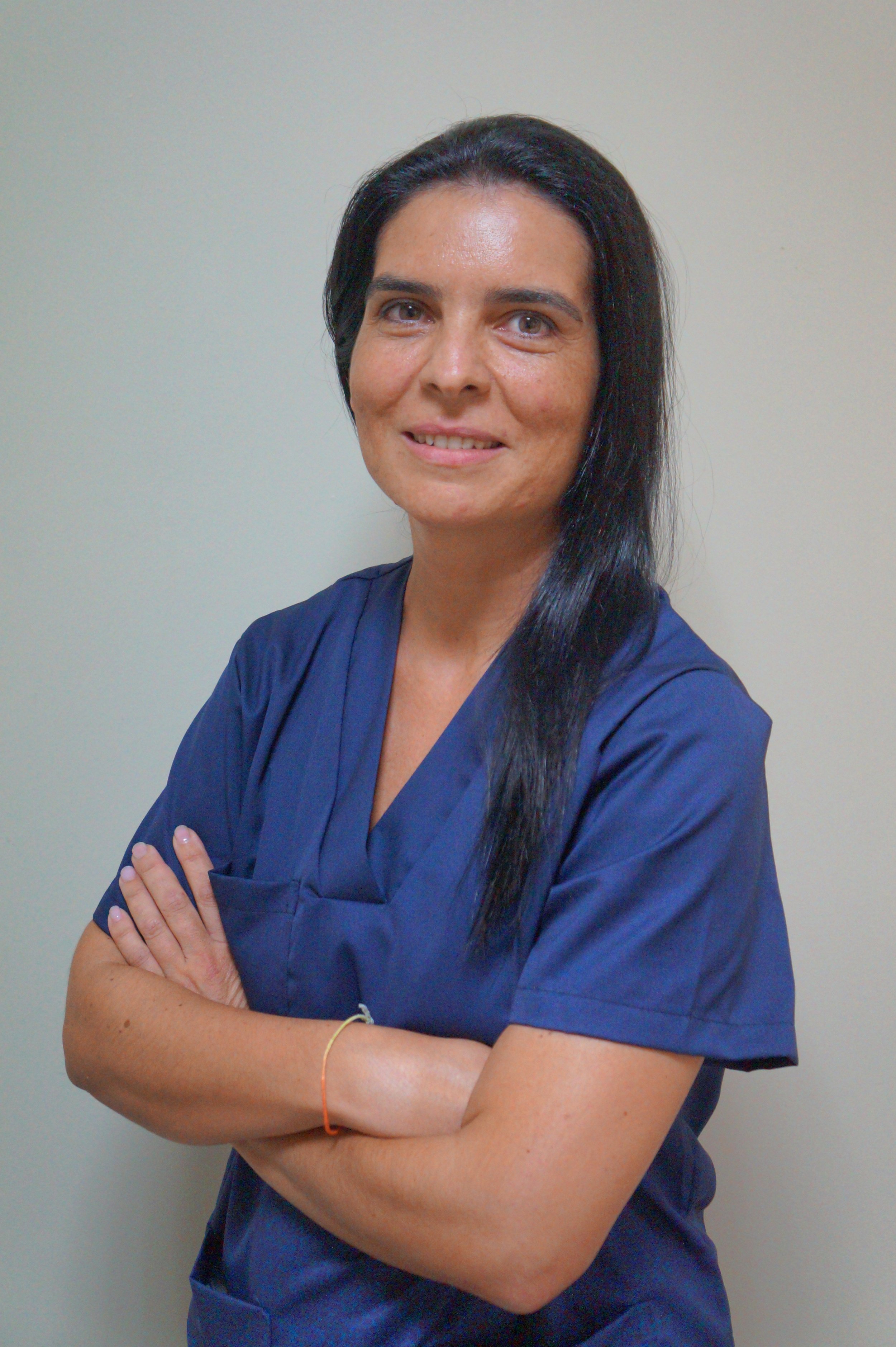 Sónia , profissional de saúde, com os braços cruzados, com parede clara como fundo.