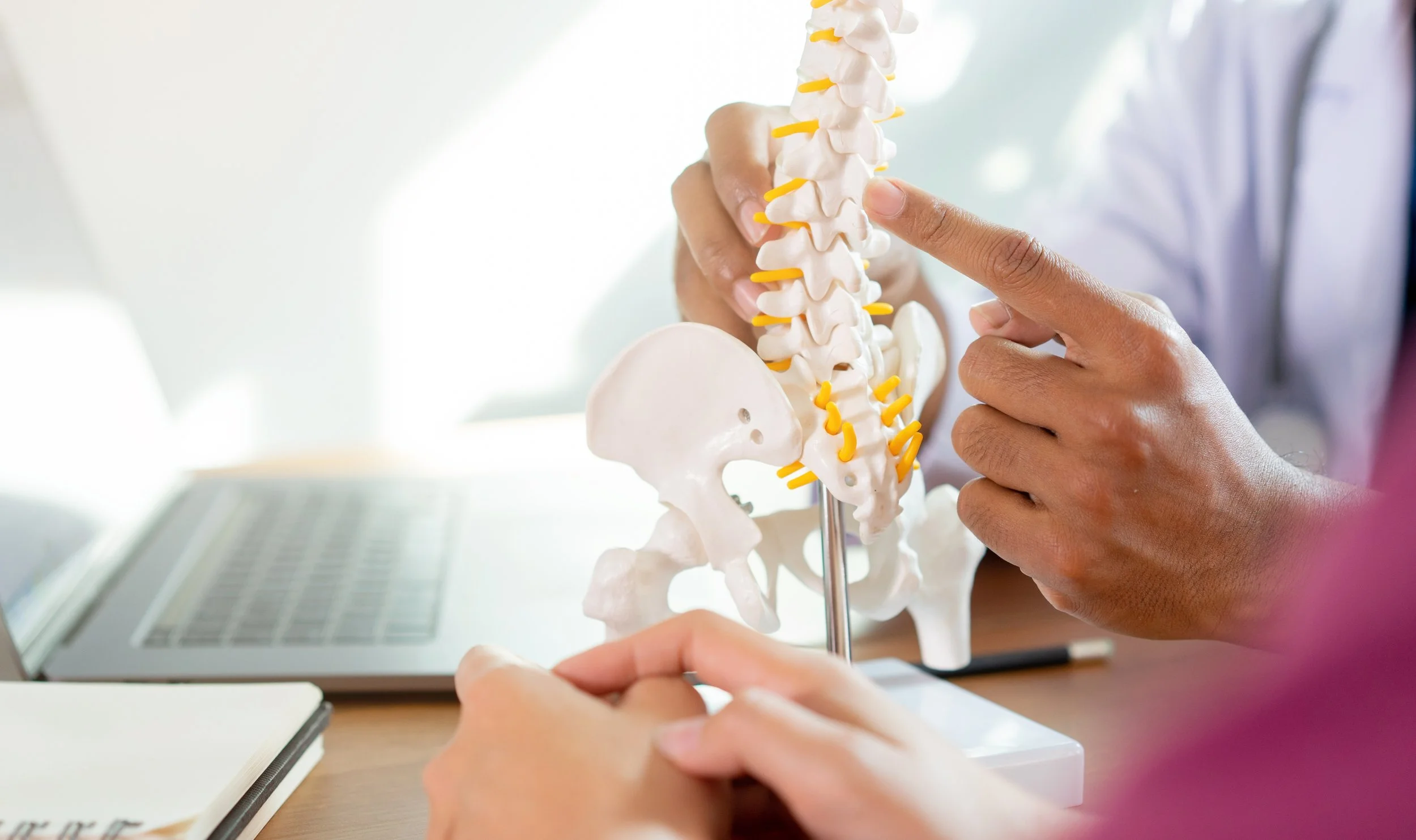 Pessoa a explicar um modelo de curvatura da coluna vertebral, devido a escoliose.