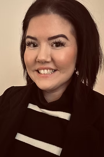 A lady with dark hair and eyebrows and smiling at the camera.