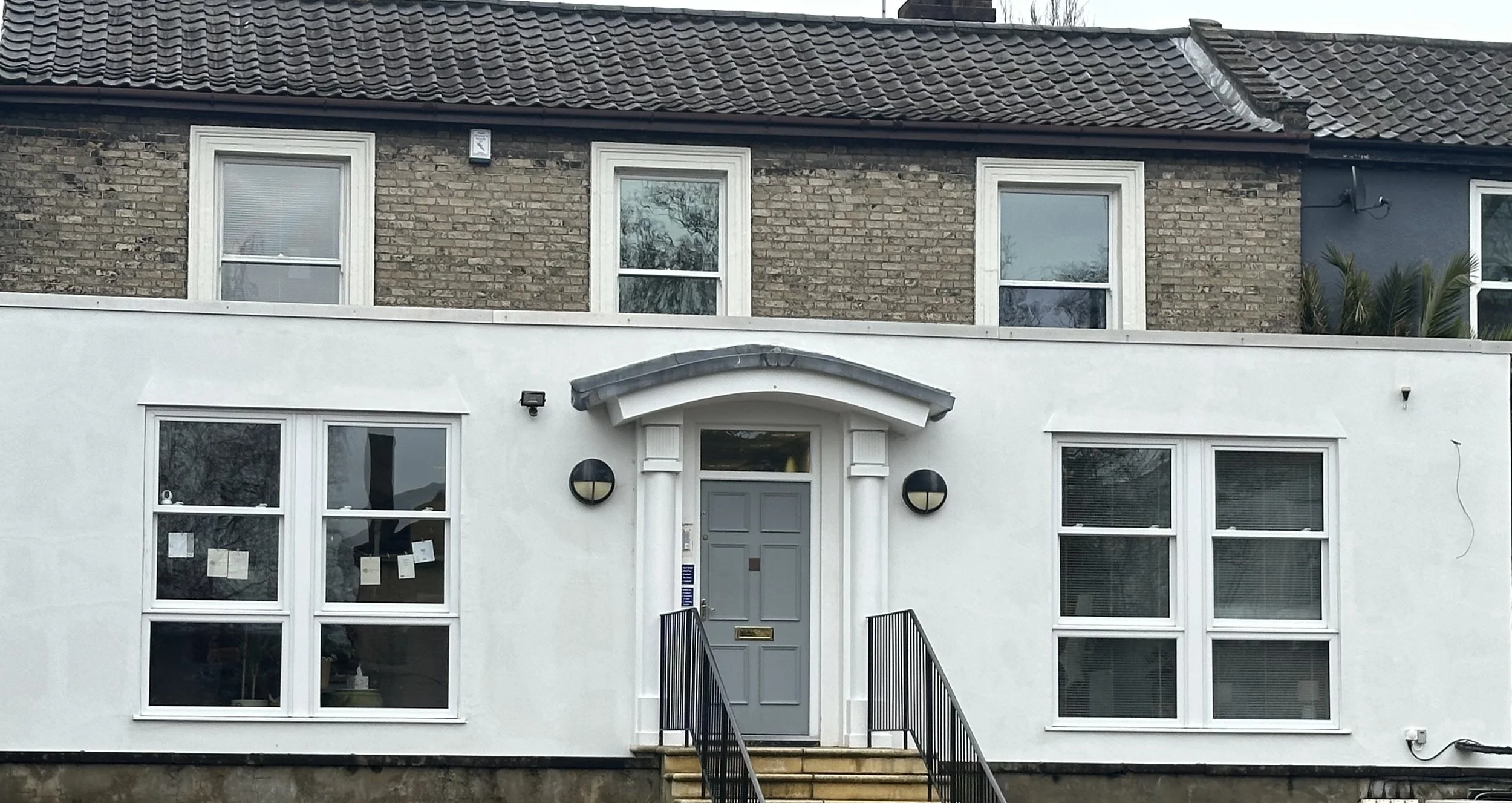 External photo of the wellbeing centre building. White building with a grey door.