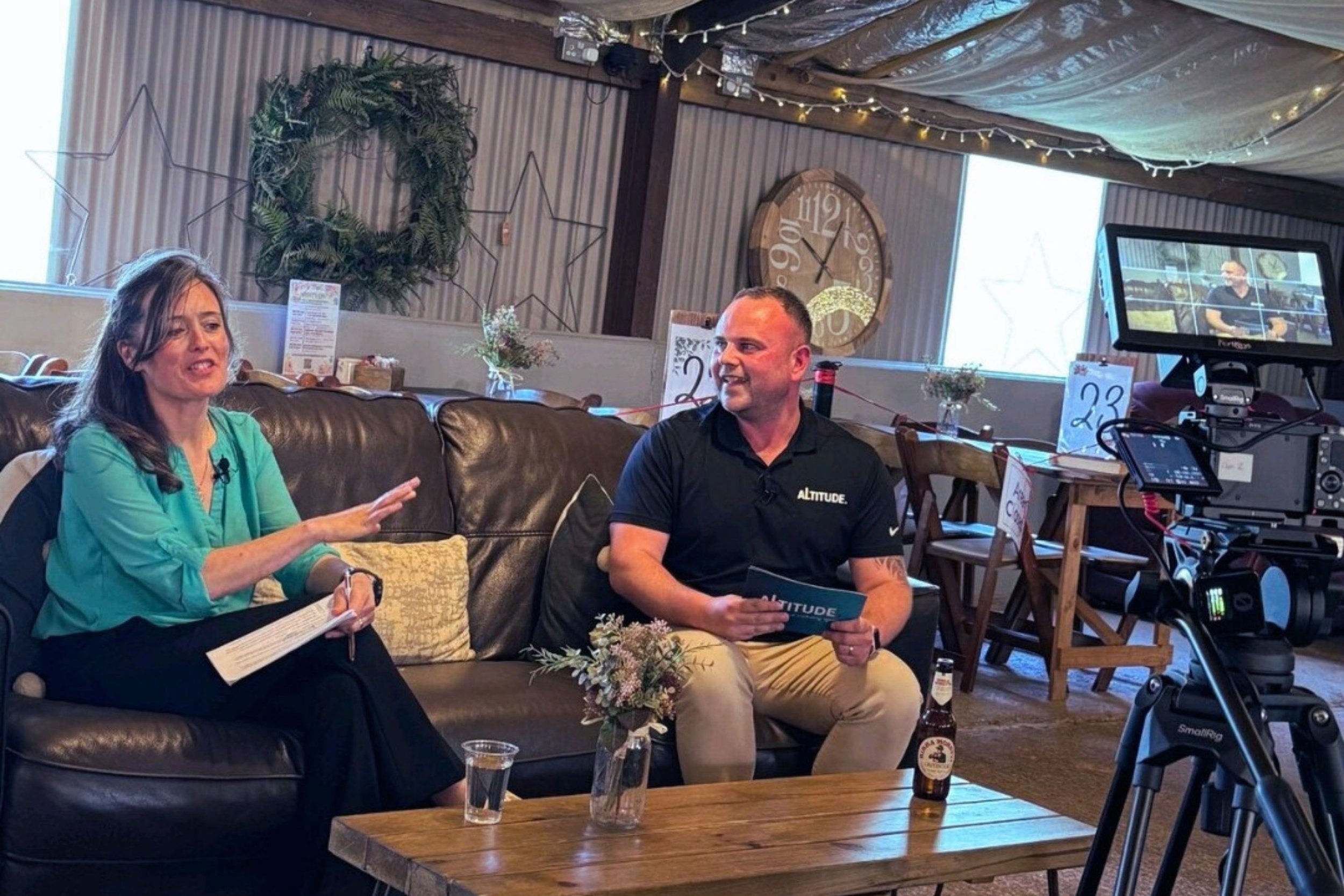 Cassie Davison speaking during a filmed keynote Q&A in an independent hospitality venue, seated on a sofa with another speaker.