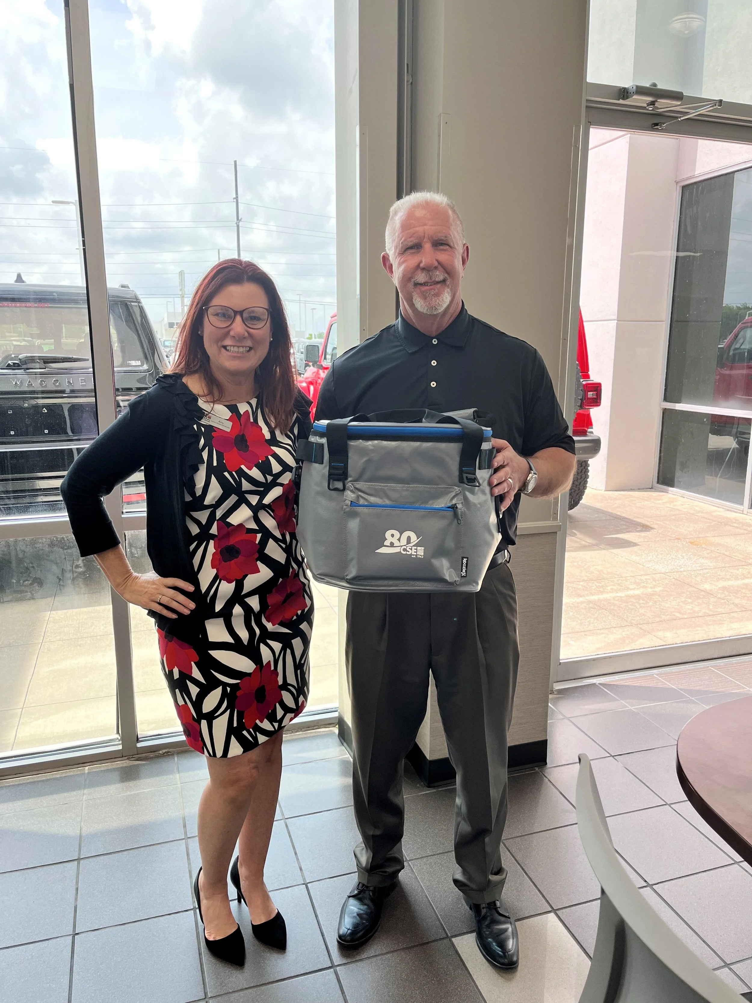 Old man and young woman celebrate 80 years of CSE with a custom bag