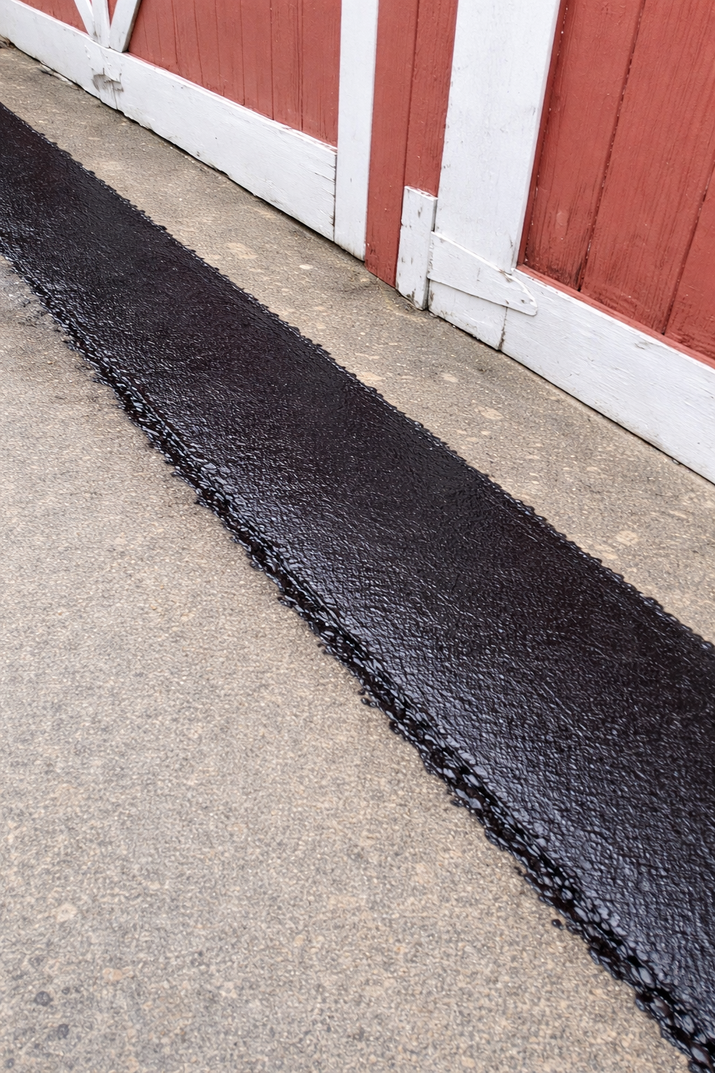 Fresh asphalt patch by garage door.png