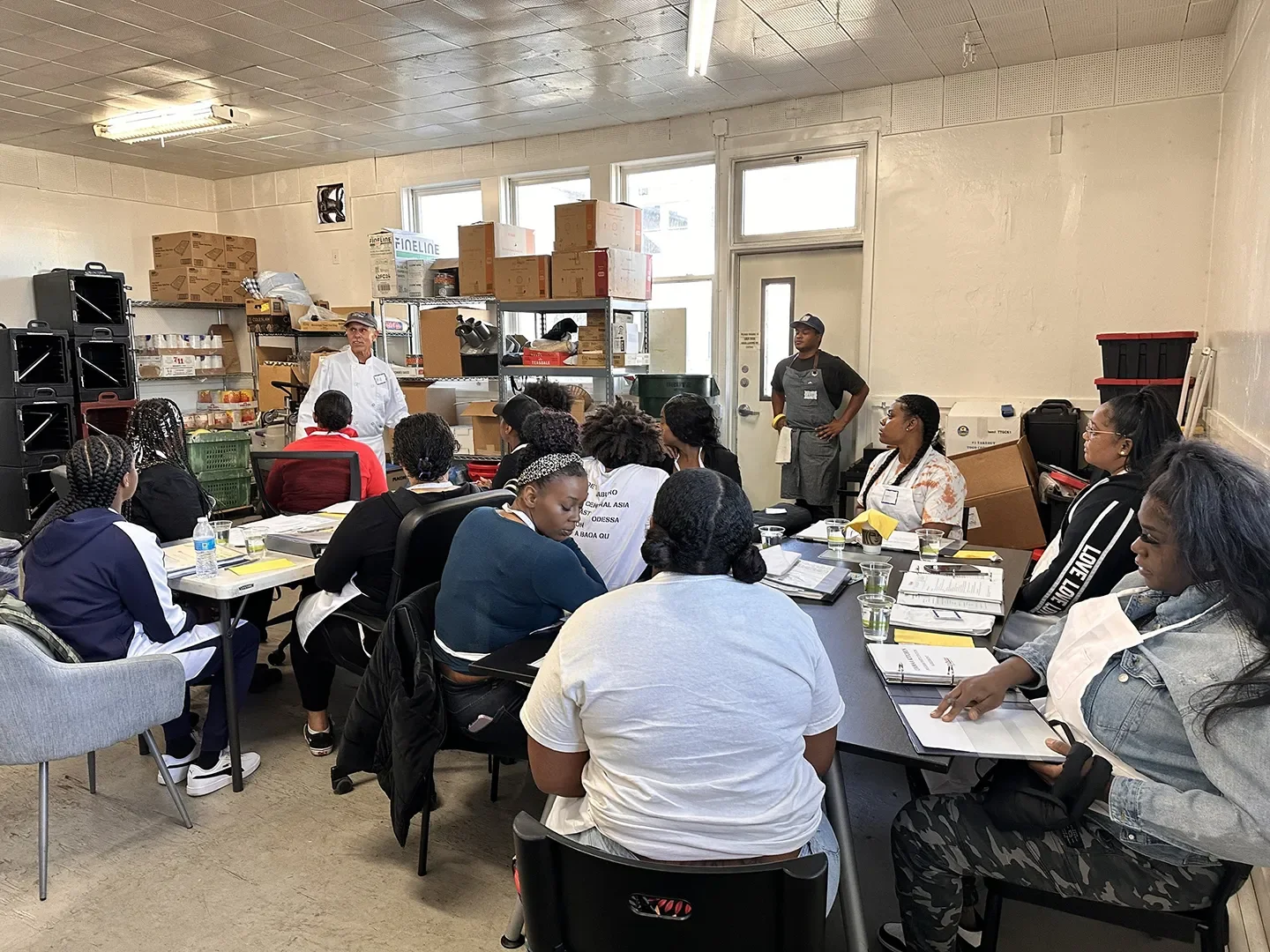 Group of people in a class, sitting at tables with books open