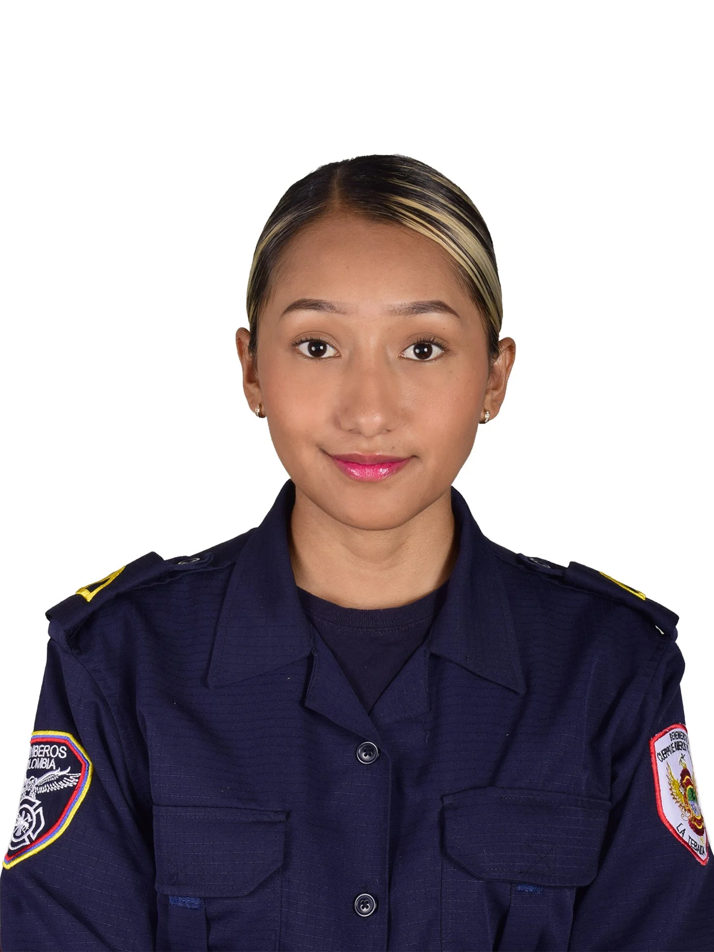 Joven mujer policía de cabello oscuro con mechas rubias, vestida con uniforme de la policía en Colombia, de fondo blanco.