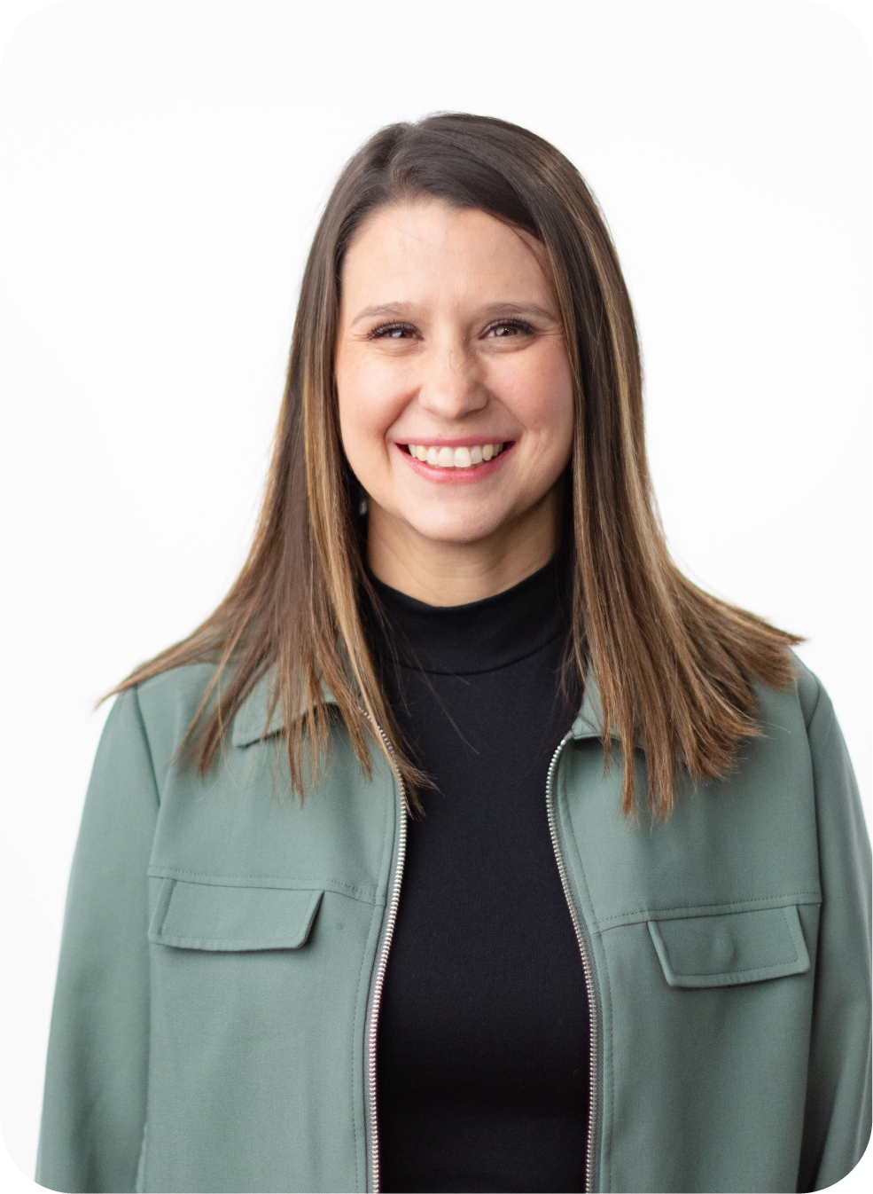 A woman with shoulder-length brown hair smiling, wearing a black turtleneck and a green jacket, against a white background.
